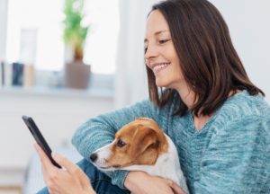 Frau mit Handy und Hund beim Download