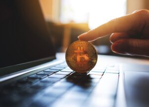 Person hält Bitcoin auf Laptop